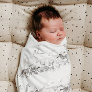 Baby being swaddled in animal print blanket.