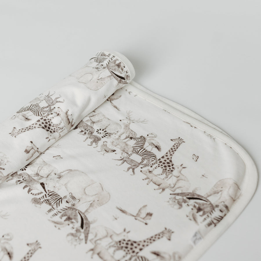 Animal print blanket lay flat with the end rolled, showing all the different animals