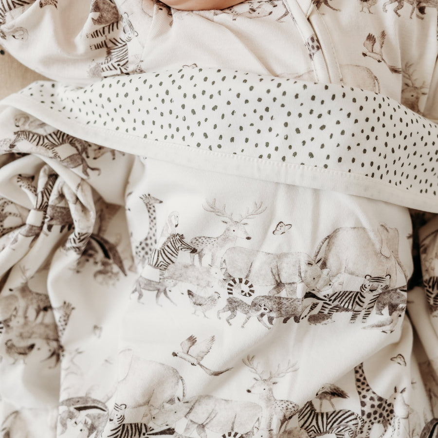 Blanket animal print covering baby clearly showing both the animal print and the inside pattern, showing off the double thickness to animal print blanket.