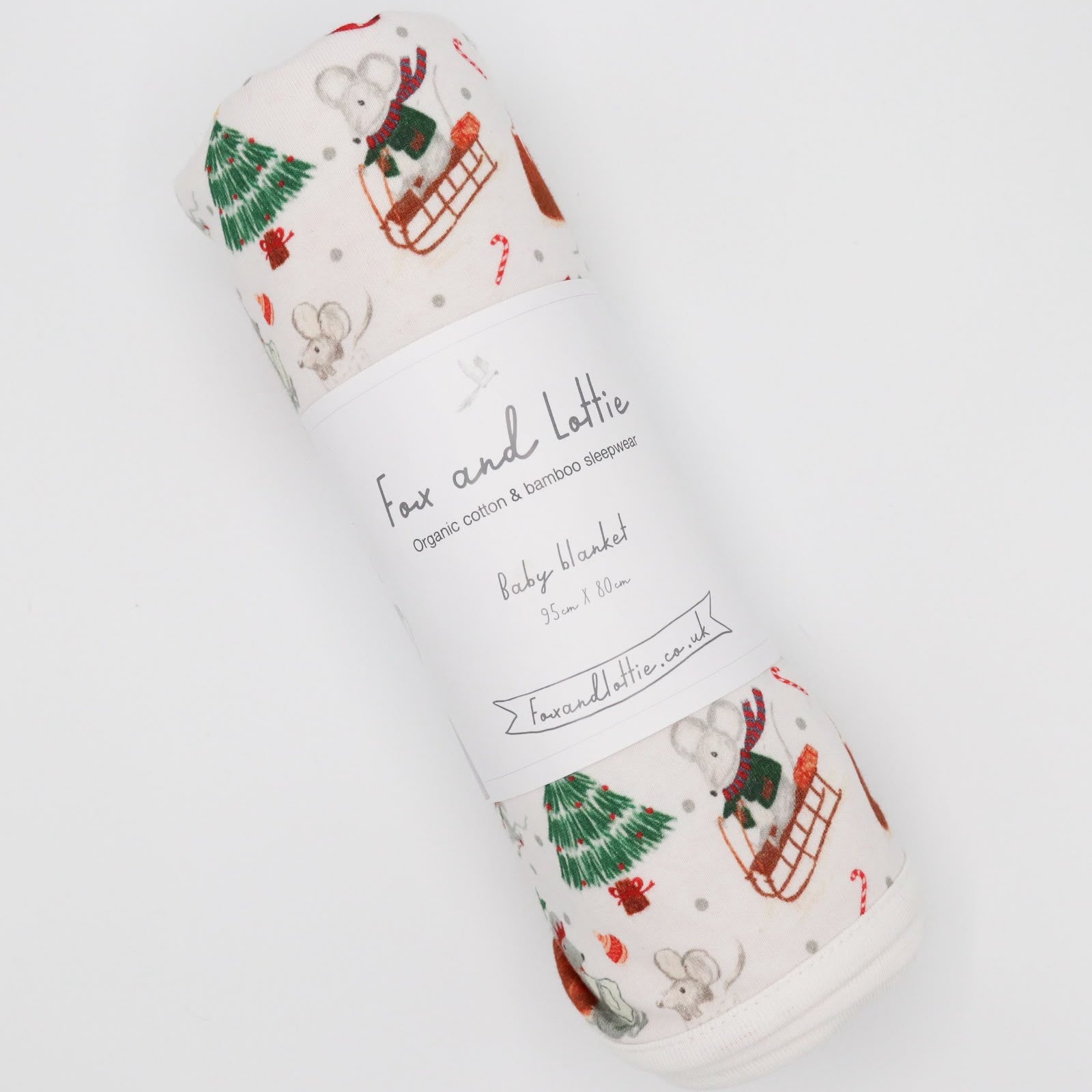A rolled baby blanket with a festive Christmas print featuring a mouse in a sled. Premium sleepwear by Fox and Lottie.