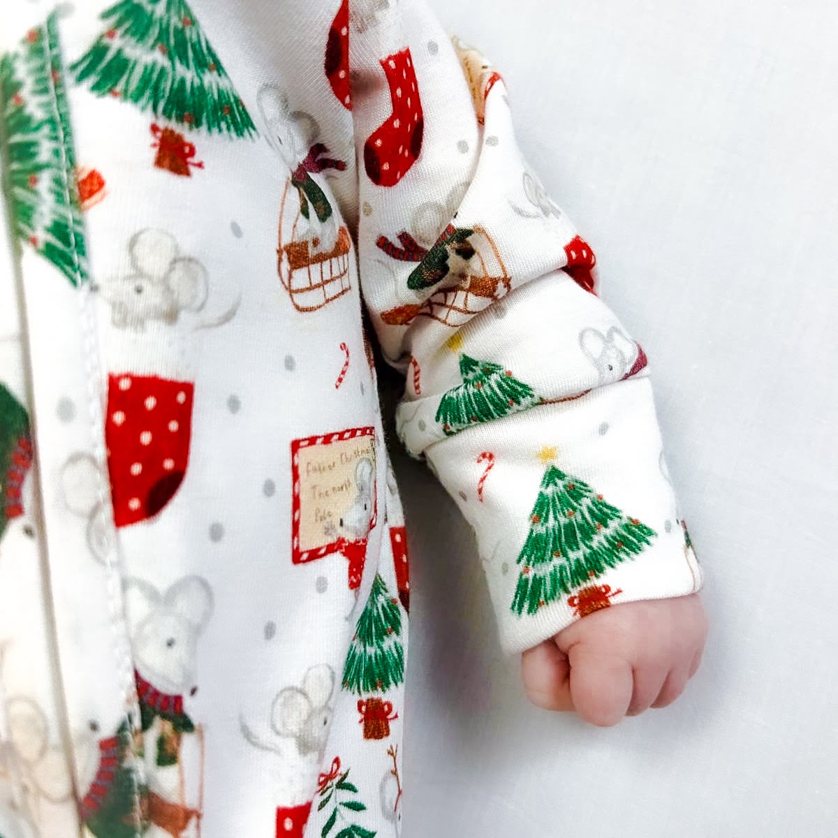 Christmas sleepsuit from Fox and Lottie close up of a baby arm showing Christmas tree and Christmas mice.