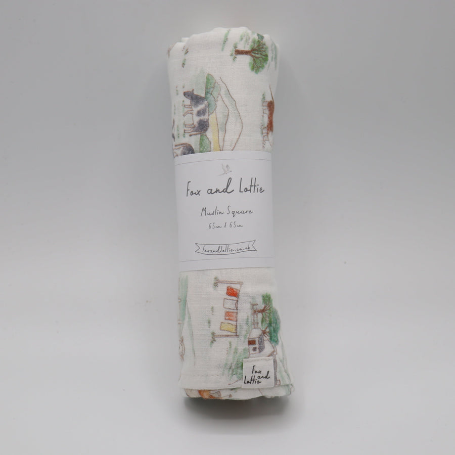 Rolled-up fabric swaddle with a label on a gray background, farm muslin