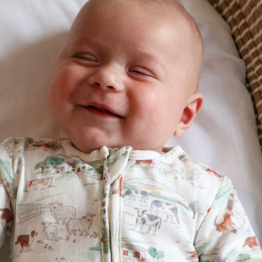 Baby laughing in farm sleepsuit